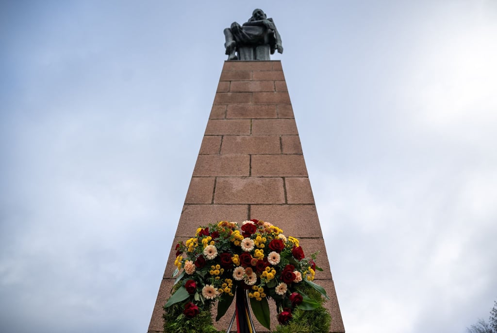 Ein Blumenkranz steht am Denkmal „Die Tragende“ am Fuß des Schwedtsees in der Mahn- und Gedenkstätte Ravensbrück.