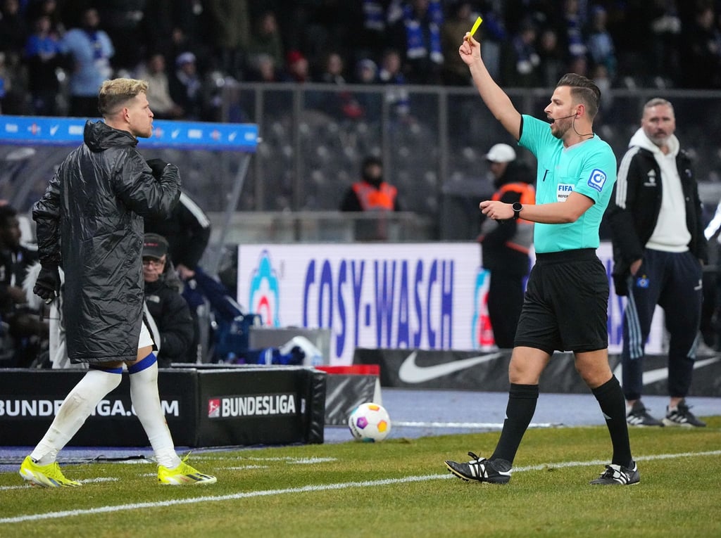 Schiedsrichter Daniel Schlager (r) zeigt dem ausgewechselten Florian Niederlechner (l) von Hertha BSC die gelbe Karte.