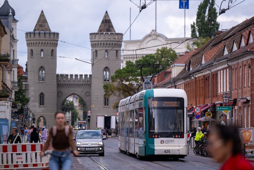 Eine Straßenbahn der Linie 92 fährt über die Friedrich-Ebert-Straße vor der Kulisse vom Nauener Tor.