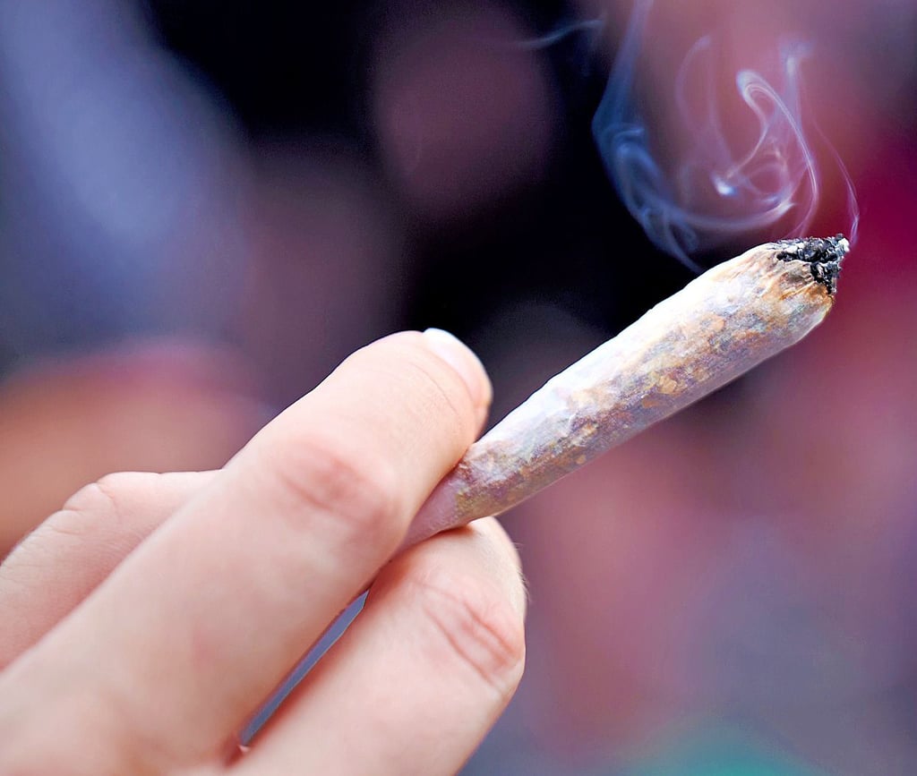 Eine Frau hält einen Joint in der Hand.