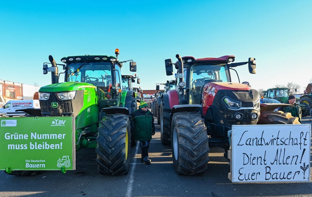 Landwirte stehen mit ihren Traktoren auf einem Parkplatz.