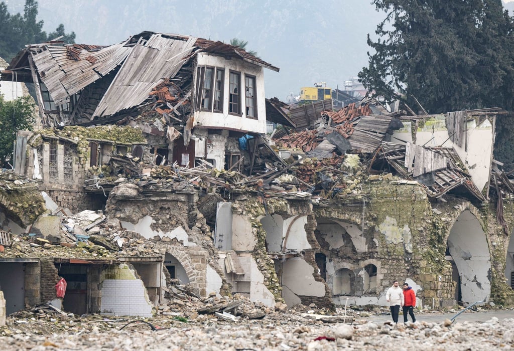 Zwei Männer gehen an einer völlig zerstörten Häuserzeile in Antakya vorbei. Im Zentrum der Stadt waren bei dem Beben vor einem Jahr unzählige Häuser zerstört oder beschädigt worden.