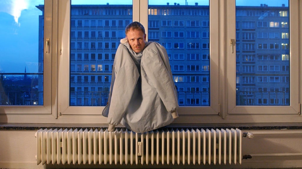 Der Schaupsieler Helmut Zhuber sitzt in einem Theaterstück mit Jacke auf der Heizung einer Großstadt-Wohnung (Archivfoto). Damit die Salzwedeler künftig vom Heizen weder arm werden noch frieren müssen, arbeitet die Stadt an einer kommunalen Wärmeplanung.