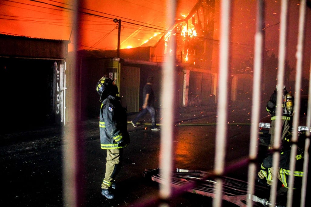 Ein Feuerwehrmann blickt nach oben, als die Flammen eines Waldbrandes auf Gebäude übergreifen.