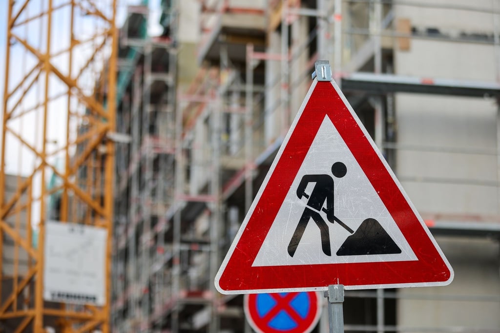 Ein Baustellenschild steht vor der Baustelle mehrerer Miethäuser. Das Wohnungsbauunternehmen Bonava baut deutschlandweit 340 Stellen ab, davon 120 im brandenburgischen Fürstenwalde.