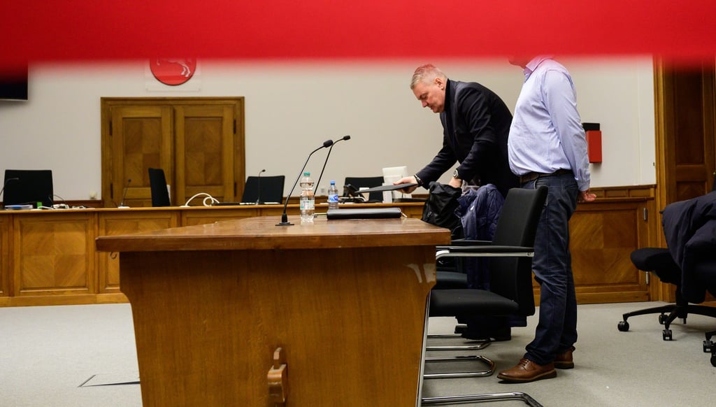 Anwalt Dirk Meinicke (l), und der Angeklagte stehen vor Prozessbeginn im Landgericht hinter rotem Absperrband.