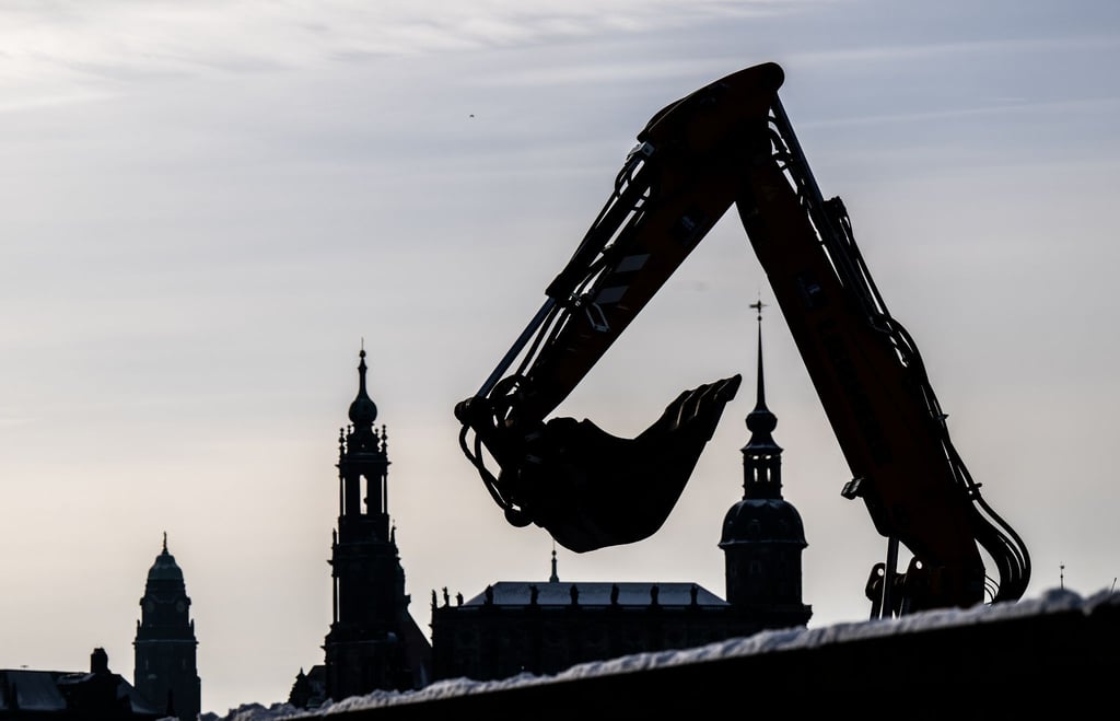 Die Schaufel eines Baggers auf einer Baustelle am Elberadweg ist vor dem Rathaus (l-r), der Hofkirche und dem Hausmannsturm zu sehen.