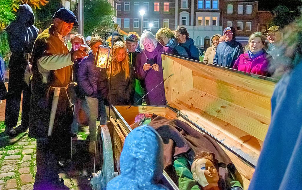 Auf dem Markt wird es bei der Führung des Nachtwächters Ulrich Pettke gruselig. Der Totengräber hat auf seinem Karren einen Sarg mit einer Hexe.