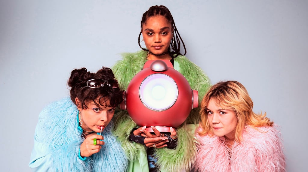 Sue (Via Jikeli, l), Peggy (Lea Drinda, r) und Izzy (Sira-Anna Faal) mit der KI aus „Boom - Eine Band, 1000 Probleme“.