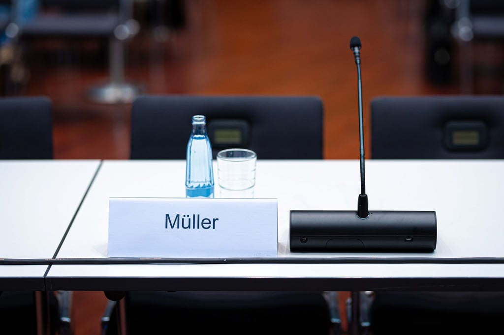 Ein Namensschild mit der Aufschrift „Müller“ steht auf einem Tisch.
