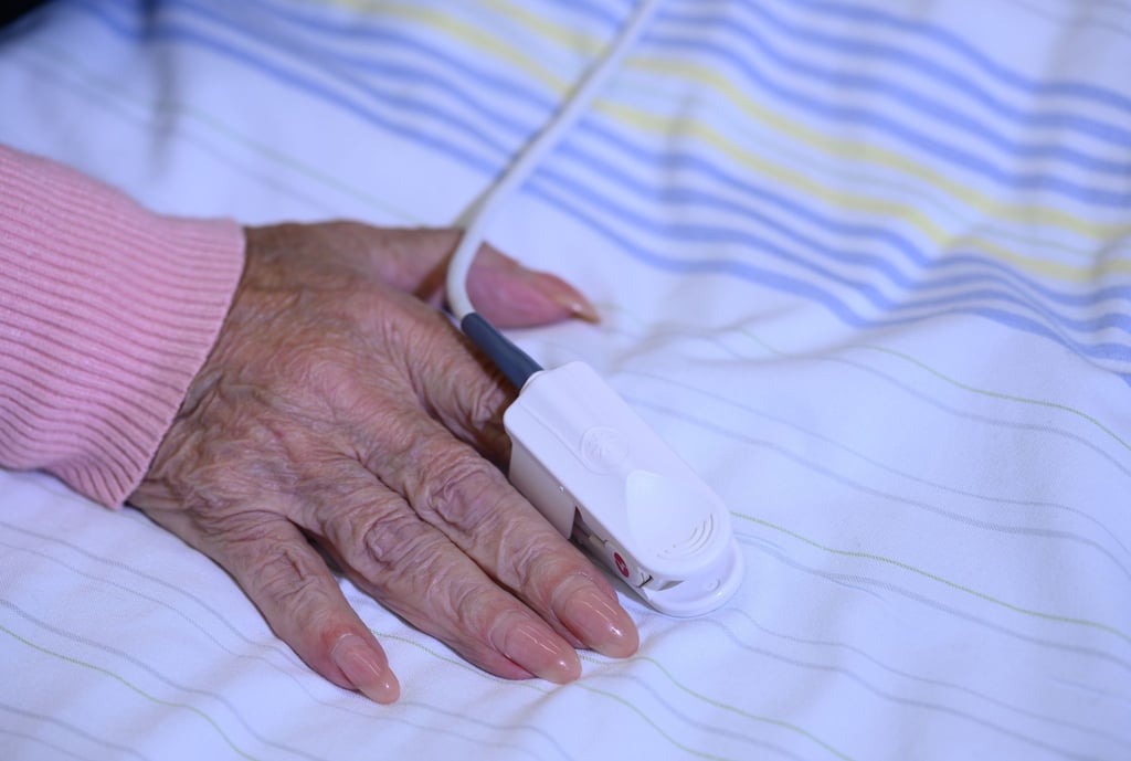 Eine Patientin auf der Station der Akutgeriatrie am Universitätsklinikum Dresden hat am Finger ein Messgerät für den Blutsauerstoff angelegt bekommen.