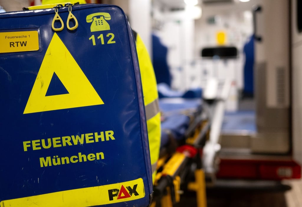 Feuerwehrleute der Berufsfeuerwehr München bereiten an der Feuerwache 1 in der Fahrzeughalle einen Krankenwagen für einen Einsatz vor.