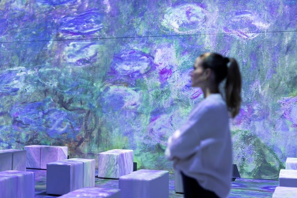 Eine Mitarbeiterin steht in der multimedialen Ausstellung „Monets Garten“.