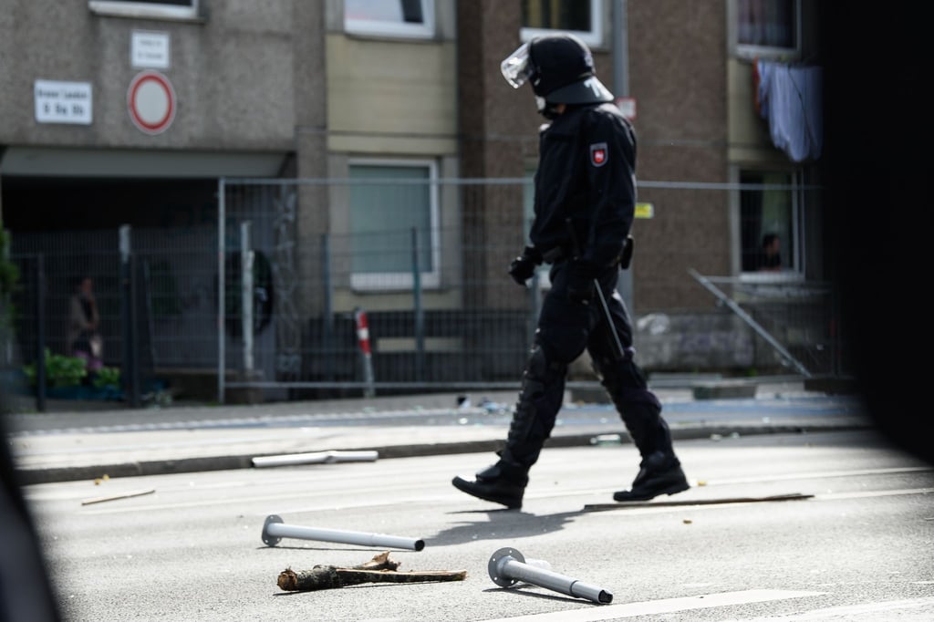 Ein Polizist geht an Metall- und Holzgegenständen vorbei, die vor einem unter Quarantäne gestellten Wohngebäude in der Göttinger Innenstadt auf dem Boden liegen.