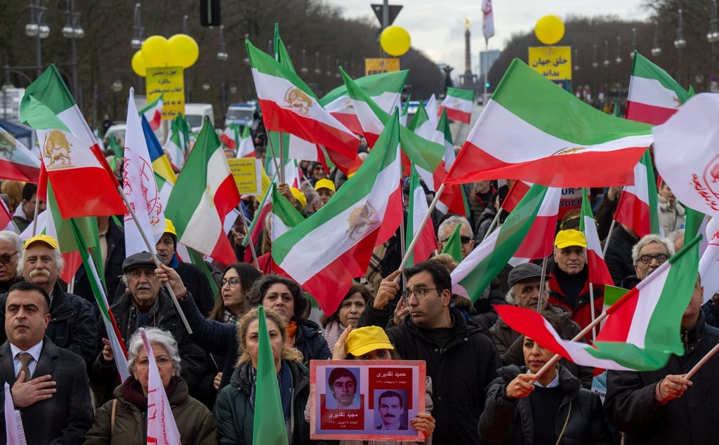 Zahlreiche Menschen schwenken Fahnen bei einer Kundgebung gegen die iranische Regierung.