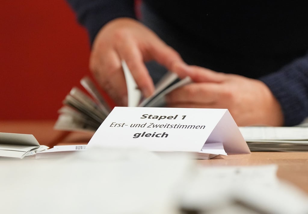 Ein Wahlhelfer sortiert bei der Stimmauszählung die Stimmzettel.