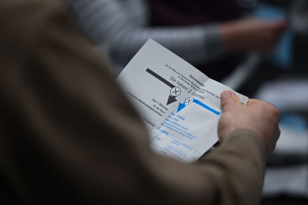 Ein Wahlhelfer hält während der Auszählung der Briefwahlstimmen einen Stimmzettel in der Hand.