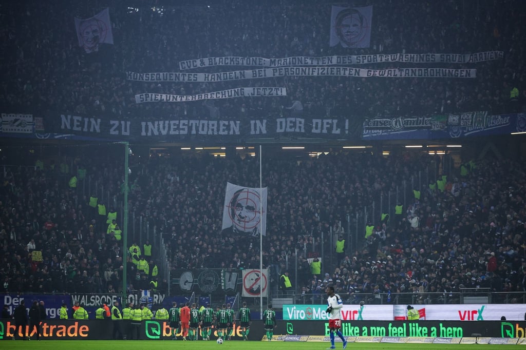 Bei einem Protest der Fans von Hannover 96 wird ein Banner mit der Aufschrift "Nein zu Investoren in der DFL!" und dem Gesicht vom Geschäftsführer des Fußball-Zweitligisten Hannover 96, M. Kind, mit einem Fadenkreuz gezeigt.