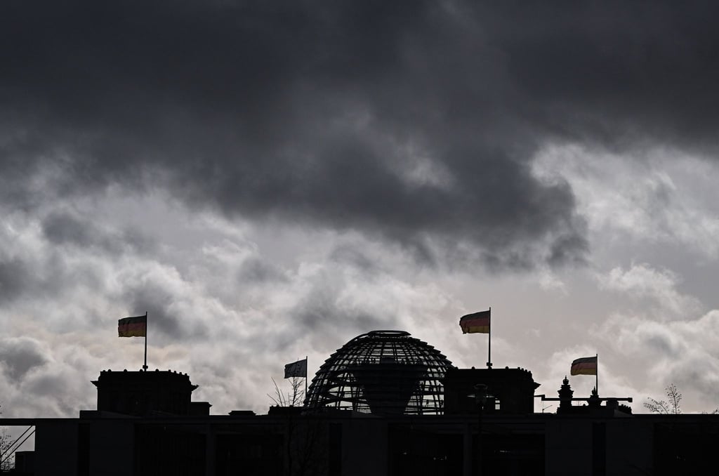 Wolken sind über der Kuppel vom Reichstag zu sehen, auf dem Deutschlandfahnen wehen.