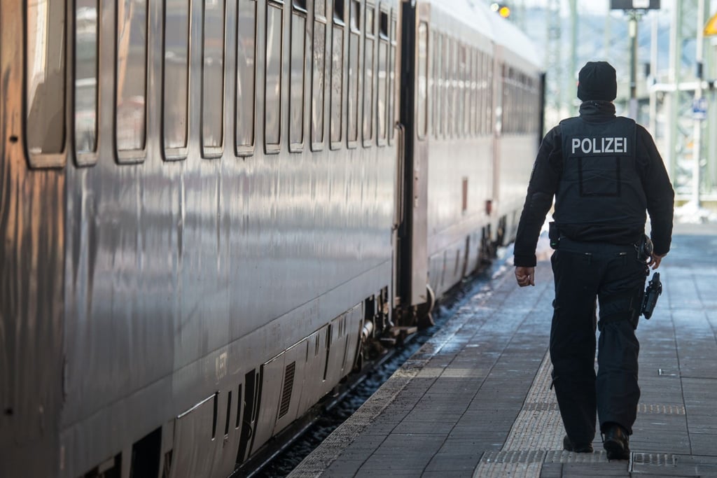 Ein Bundespolizist geht am Bahnhof neben einem Zug.