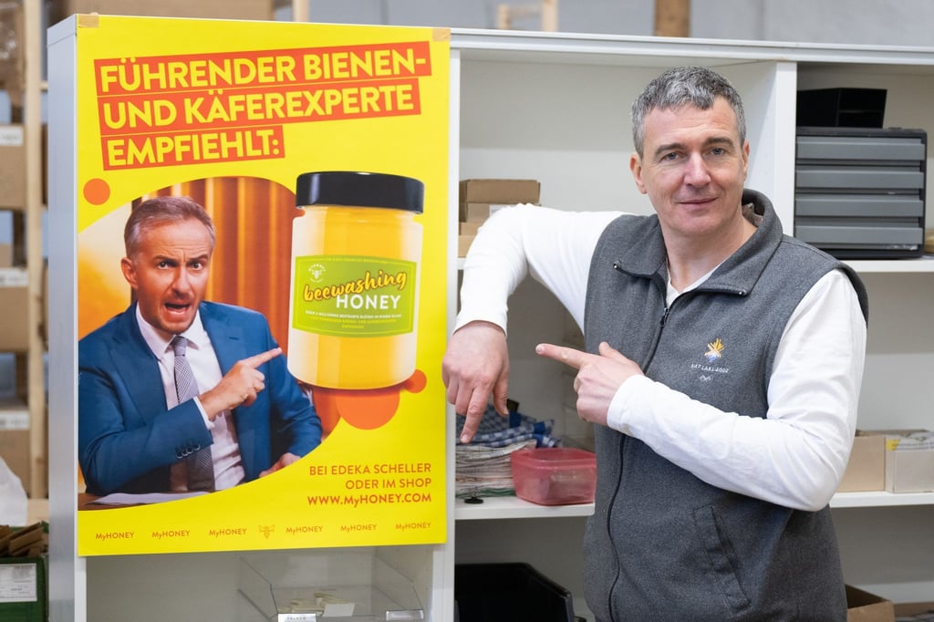 Rico Heinzig, Imker, steht neben einem Plakat mit dem Foto des Moderators Jan Böhmermann.