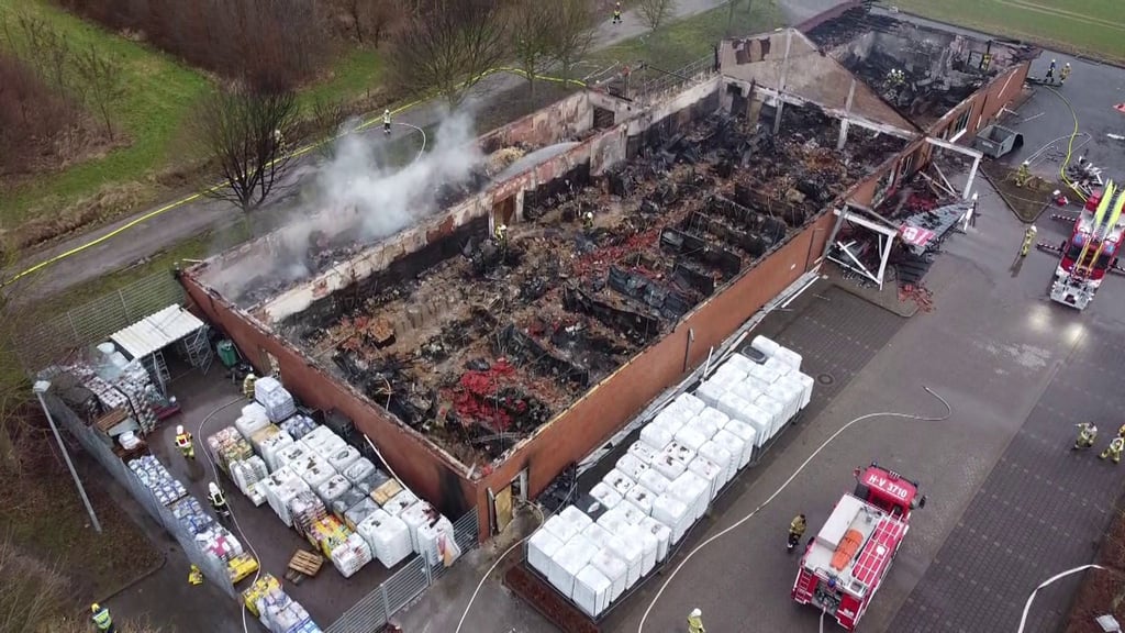 Rauch steigt aus der Ruine eines Baumarktes, die Feuerwehr ist im Einsatz.