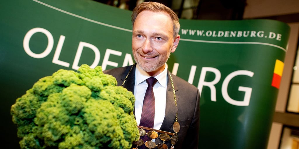 Christian Lindner (FDP), Bundesfinanzminister, trägt eine Kohlkette und hält eine Grünkohlpflanze, auch bekannt als „Oldenburger Palme“, in den Händen.
