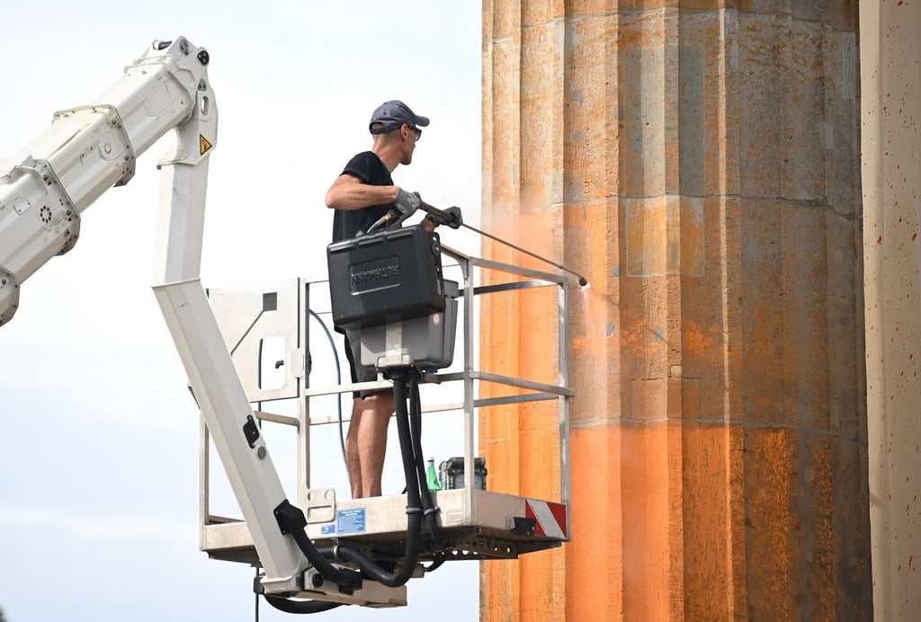 Ein Arbeiter entfernt die Farbrückstände am Brandenburger Tor.