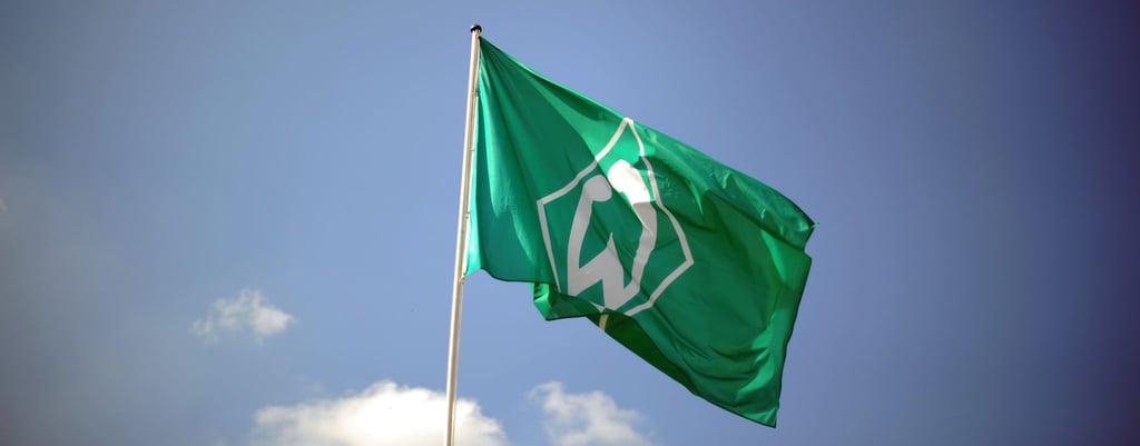 Eine Fahne mit dem Vereinslogo des Fußball-Bundesligisten SV Werder Bremen weht im Wind.