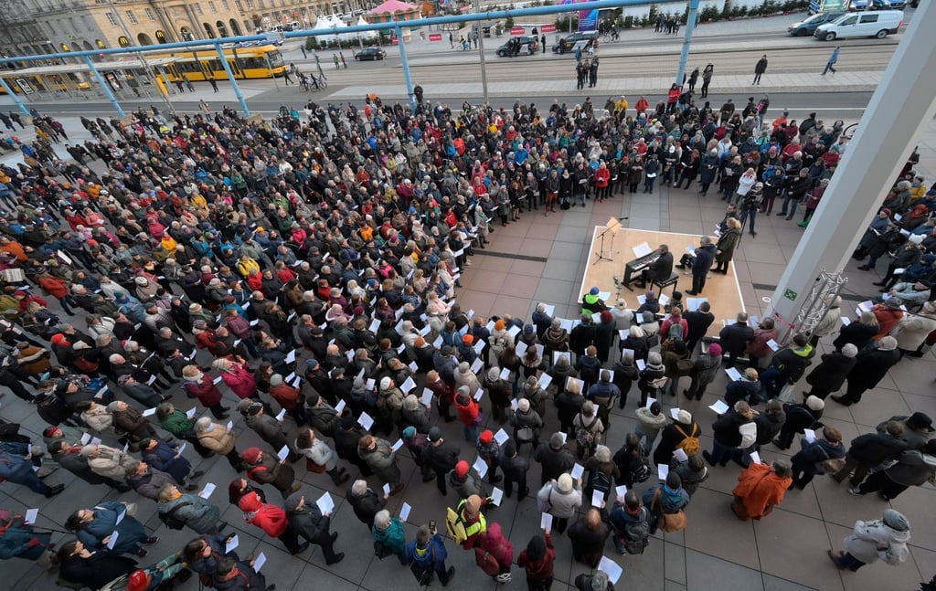 Menschen treffen sich am Gedenktag zum gemeinsamen Singen vor dem Dresdner Kulturpalast.