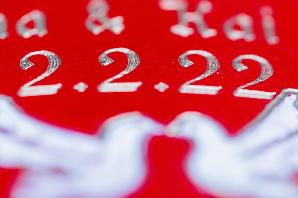 Ein sogenanntes Liebesschloss mit der Aufschrift "Anna & Kai 2.2.22" hängt an einer Brücke.
