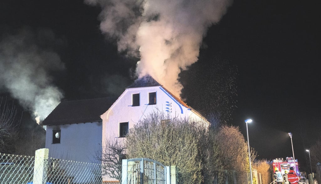 Feuerwehrleute löschen ein brennendes Haus.