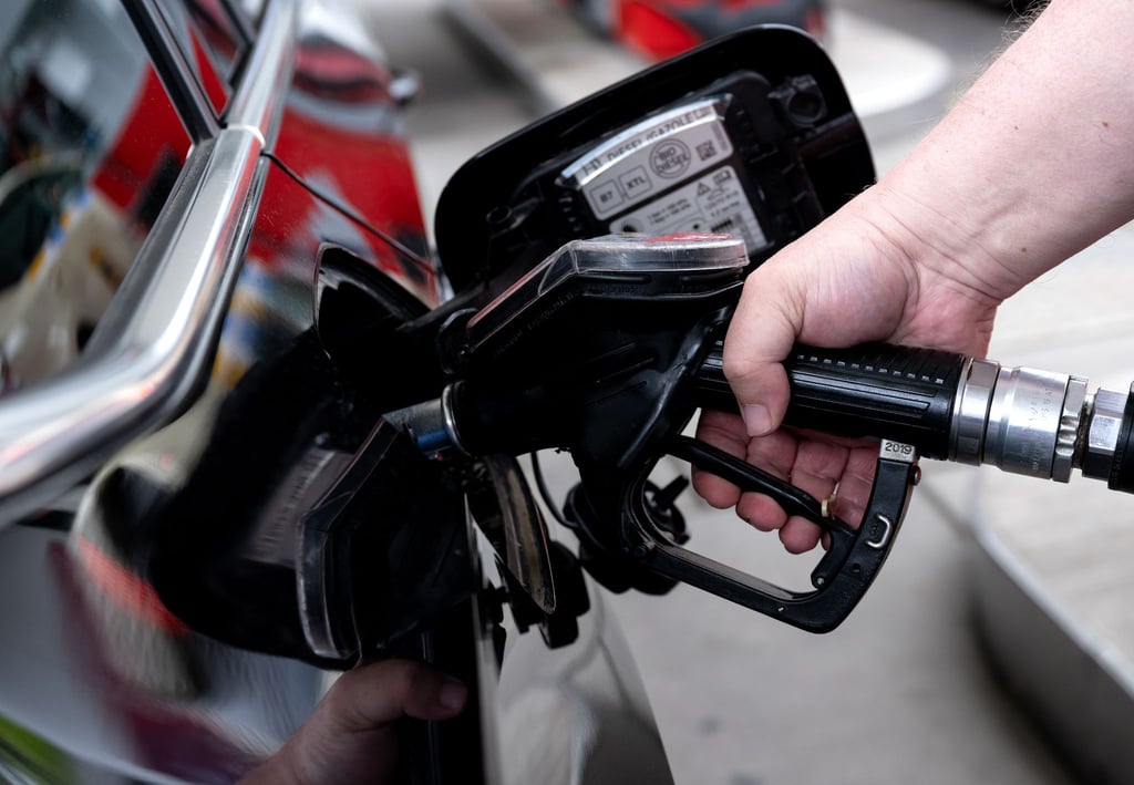Ein Mann hält eine Zapfpistole an einer Tankstelle in der Hand und betankt sein Auto.