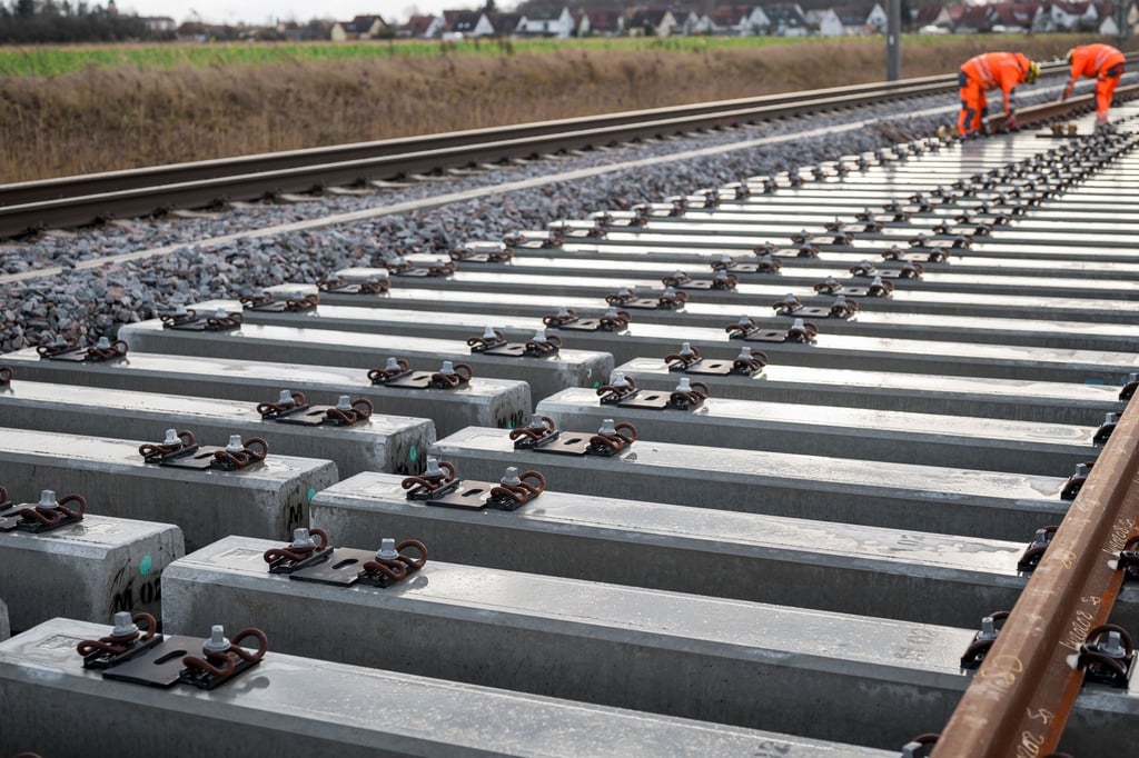 Arbeiter verlegen Gleise an einer Bahnbaustelle einer ICE-Strecke.