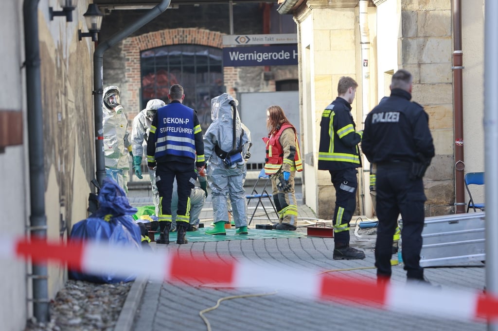 Einsatzkräfte der Feuerwehr stehen im ABC-Schutzanzug auf dem Hauptbahnhof in Wernigerode.