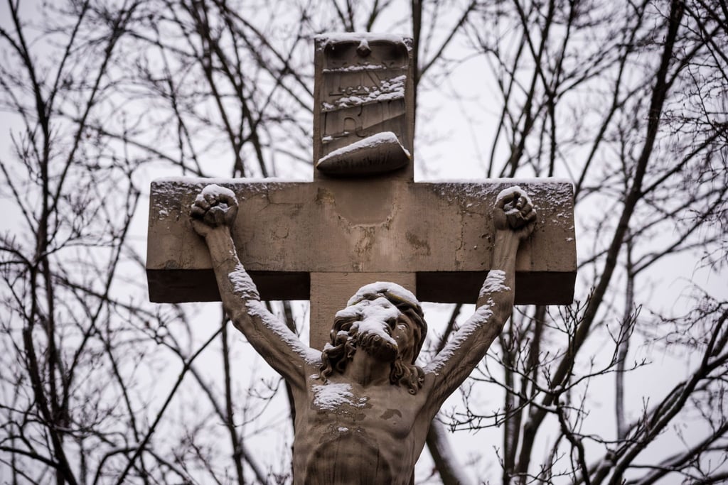Eine Figur von Jesus am Kreuz ist mit Schnee bedeckt.
