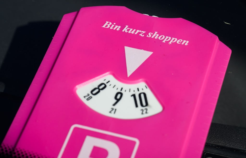 Eine pinke Parkscheibe mit Aufschrift „Bin kurz shoppen“ liegt in einem Auto in der Innenstadt.