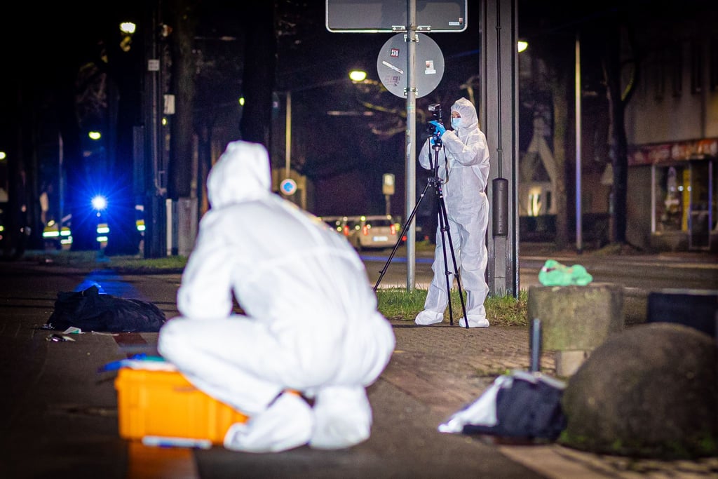 Mitarbeiterinnen des Kriminaldauerdienst (KDD) sichern auf einem Gehweg im Stadtteil Döhren in Hannover Spuren nach der Auseinandersetzung.