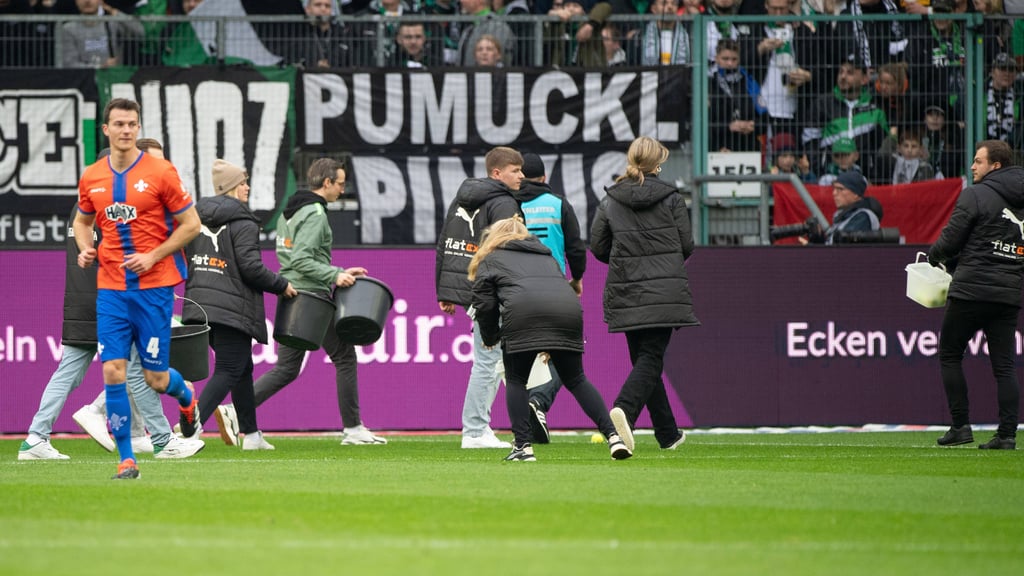 Helfer sammeln Tennisbälle der Gladbach-Fans ein.