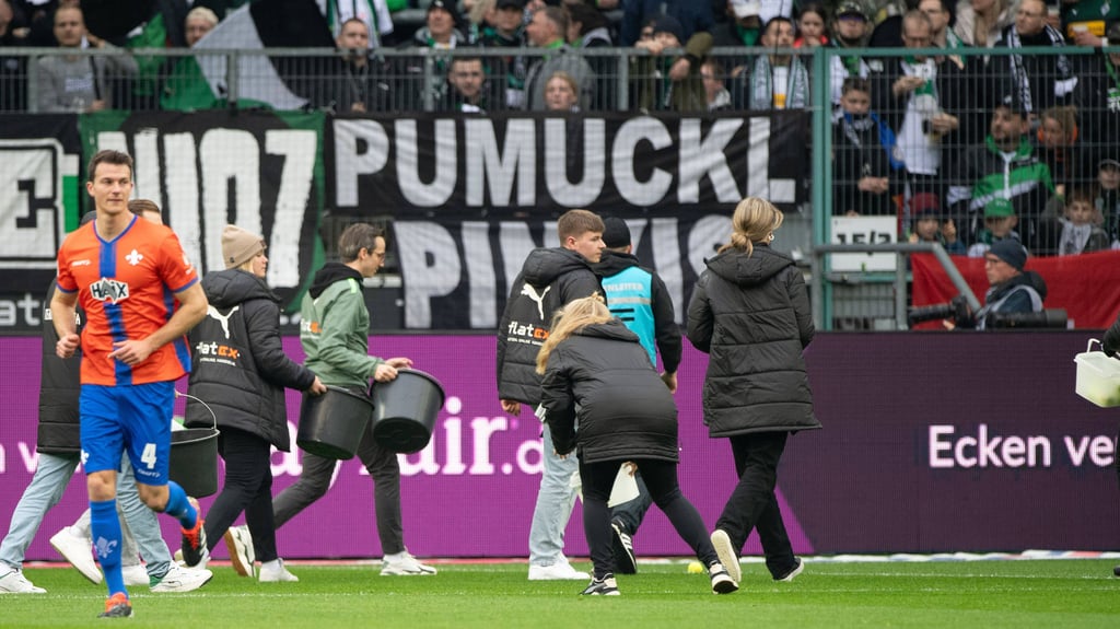 Helfer sammeln Tennisbälle der Gladbach-Fans ein.