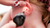 Mit einem Otoskop untersucht eine Kinderärztin ein Ohr eines Mädchens im Rahmen einer U9-Untersuchung.