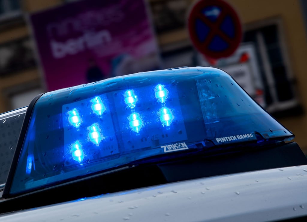 Ein Polizeiauto fährt mit Blaulicht über eine Straße.