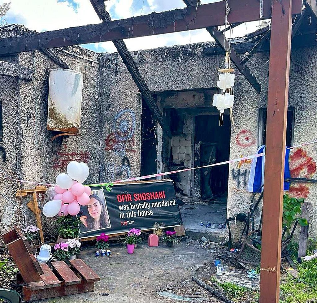 Plakate vor den zerstörten Häusern in Kfar Aza zeigen, wer in ihnen von den Hamas-Terroristen ermordet wurde.
