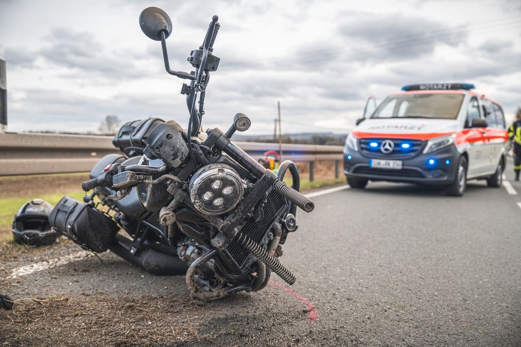 Ein beschädigtes Motorrad liegt nach einem schweren Motorradunfall vor einem Notarztwagen auf der Straße.