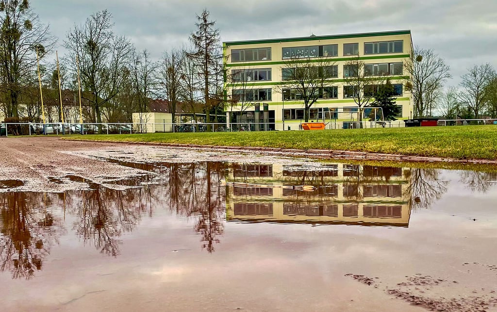 Gommerns Sekundarschule „Fritz Heicke“ spiegelt sich in einer Pfütze. Eigentlich ein schönes Motiv, wenn sich die Pfütze nicht direkt auf der Laufbahn des Sportforums befinden würde. Das stehende Wasser und der matschige Untergrund verdeutlichen, wie wichtig der Austausch der Laufbahn ist. Daher wird noch in diesem Jahr eine Tartanbahn verlegt, was Vereinssportler und Schüler freuen dürfte.