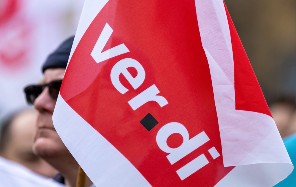Fahnen der Dienstleistungsgewerkschaft Verdi schwenken Teilnehmer auf ihrer Warnstreikkundgebung in der Innenstadt von Halle/Saale.