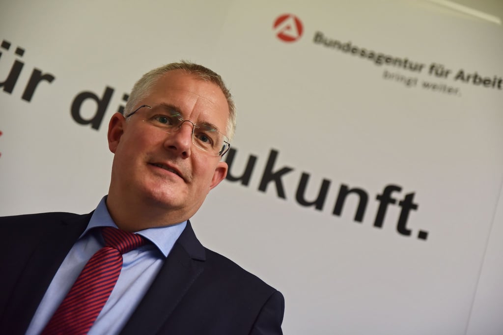 Markus Behrens, Leiter der Regionaldirektion der Bundesarbeitsagentur , steht in seinem Büro vor einer Plakatwand der Arbeitsagentur.