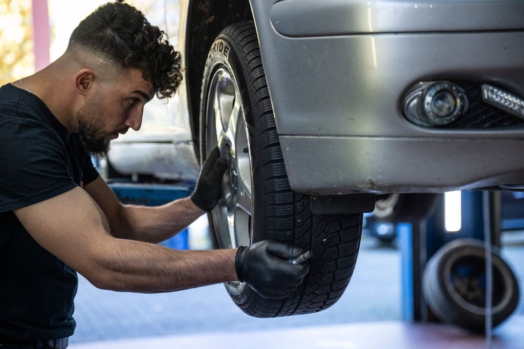 Ein Mechaniker montiert einen Autoreifen an einem Auto in einer Kfz-Werkstatt in Berlin.