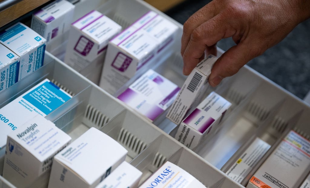 Ein Apotheker holt eine Medikamentenverpackung aus einer Schublade in einer Apotheke.