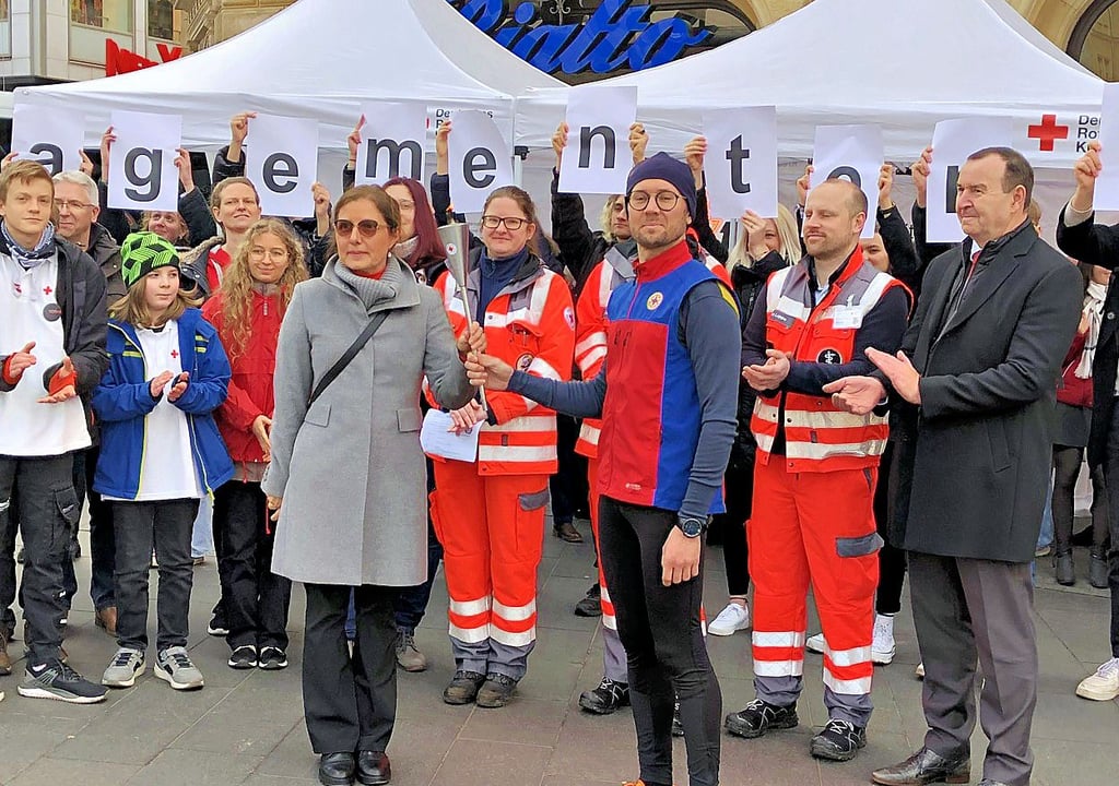 Arne Peters hat die DRK-Fackel auf dem Markplatz in Halle an Katja Fischer übergeben, Die Hallenserin leitet die Freiwilligendienste der Organisation.